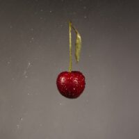 A red apple hanging from a string in the air