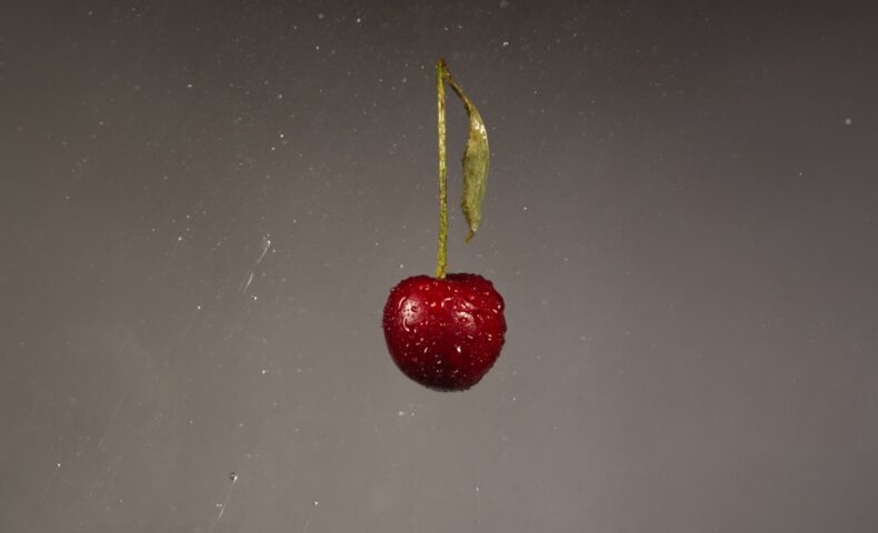 A red apple hanging from a string in the air