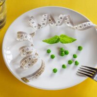 A white plate topped with peas and measuring tape