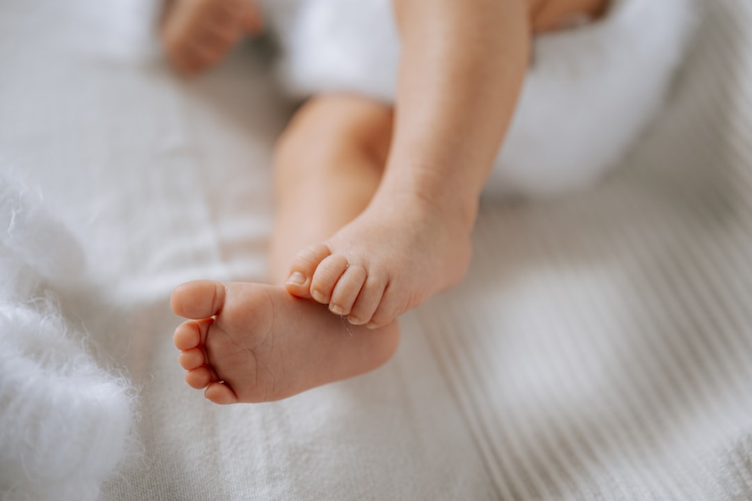 Baby's tiny feet rest on a soft white blanket.