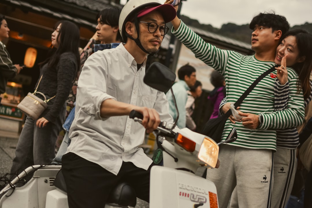 Man rides a scooter while people playfully interact.