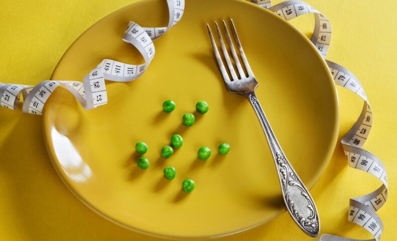 a plate with a fork, measuring tape and green peas