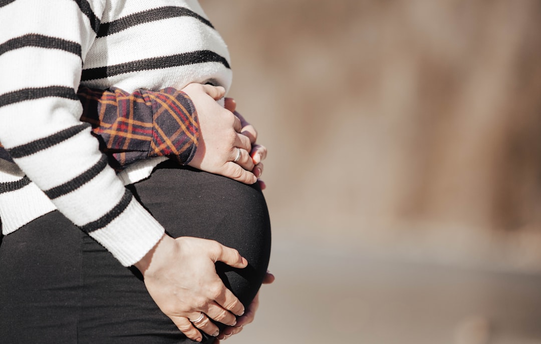 A pregnant woman in a striped shirt and black pants