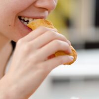 woman eating bread during daytime