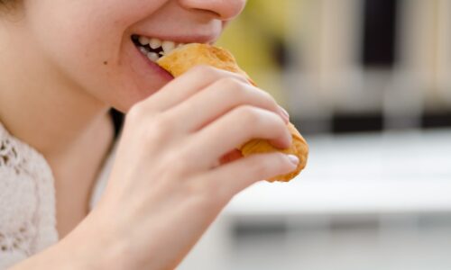 woman eating bread during daytime