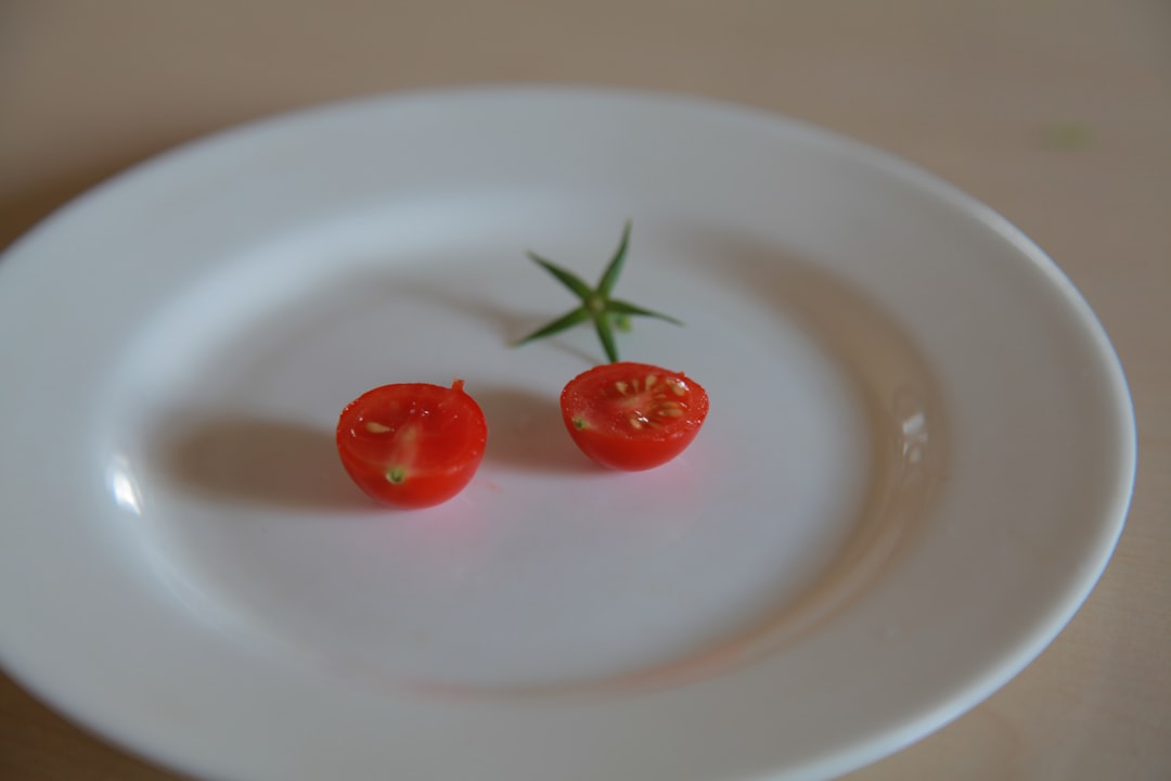 three red tomato on white ceramic plate