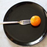 a black plate with a fork and an orange on it