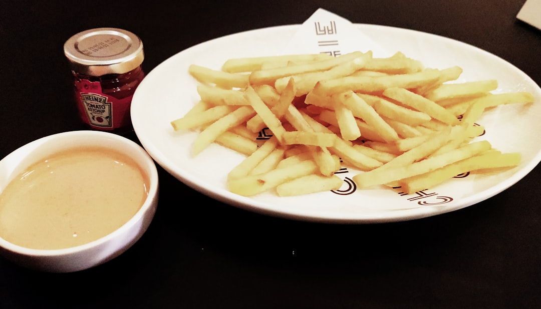 a white plate topped with french fries next to a cup of sauce