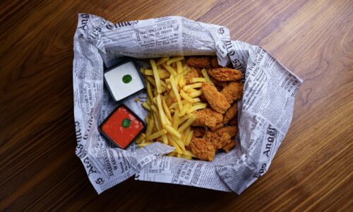 A paper bag filled with food on top of a wooden floor