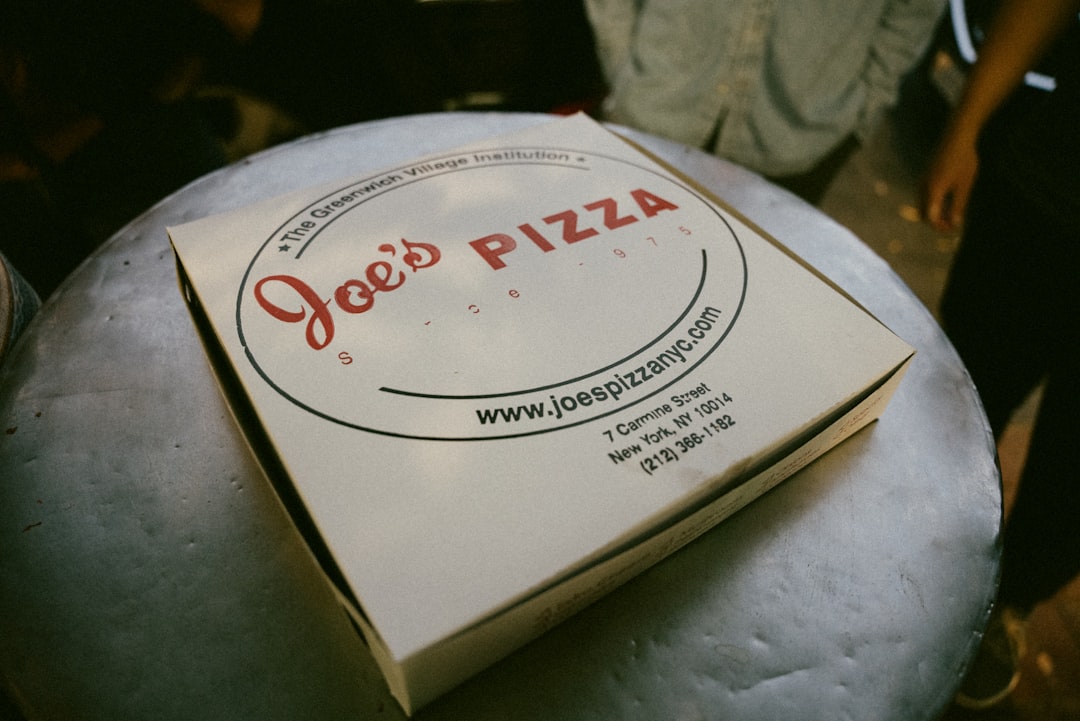 A pizza box sitting on top of a white pillow