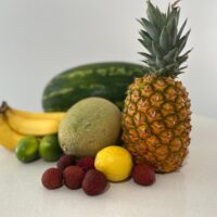 A table topped with a pineapple, bananas, and other fruits
