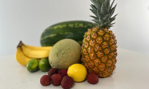 A table topped with a pineapple, bananas, and other fruits