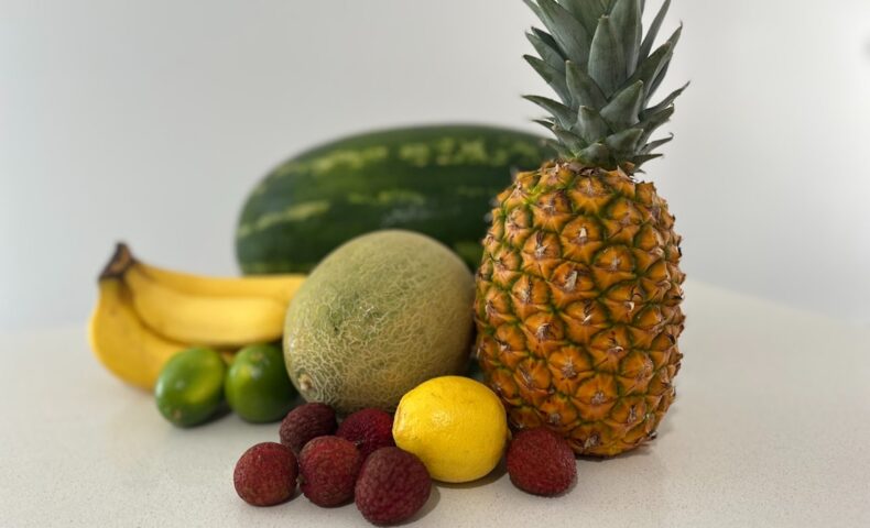 A table topped with a pineapple, bananas, and other fruits
