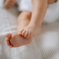 Baby's tiny feet rest on a soft white blanket.