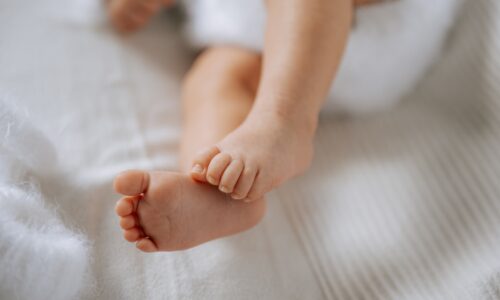 Baby's tiny feet rest on a soft white blanket.