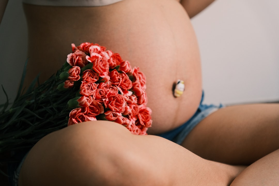 A pregnant woman holds flowers against her belly.