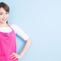 ピンクのエプロンを着た女性が笑顔で親指を立てる｜授乳中の産後ダイエットを応援する明るいママのイメージ