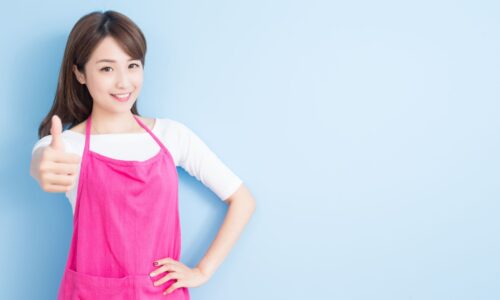 ピンクのエプロンを着た女性が笑顔で親指を立てる｜授乳中の産後ダイエットを応援する明るいママのイメージ