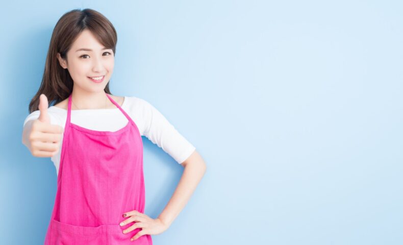 ピンクのエプロンを着た女性が笑顔で親指を立てる｜授乳中の産後ダイエットを応援する明るいママのイメージ