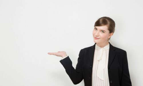 スーツ姿の女性が手のひらを見せながらプレゼンテーションをする様子