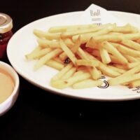a white plate topped with french fries next to a cup of sauce