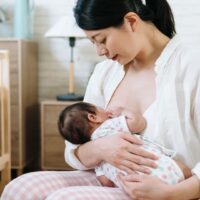 授乳中の母親が赤ちゃんを優しく抱きながら母乳を与えているシーン