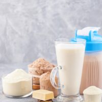 プロテインパウダーやシェイクが並んだテーブル。産後の安全なプロテインダイエットを象徴する画像。